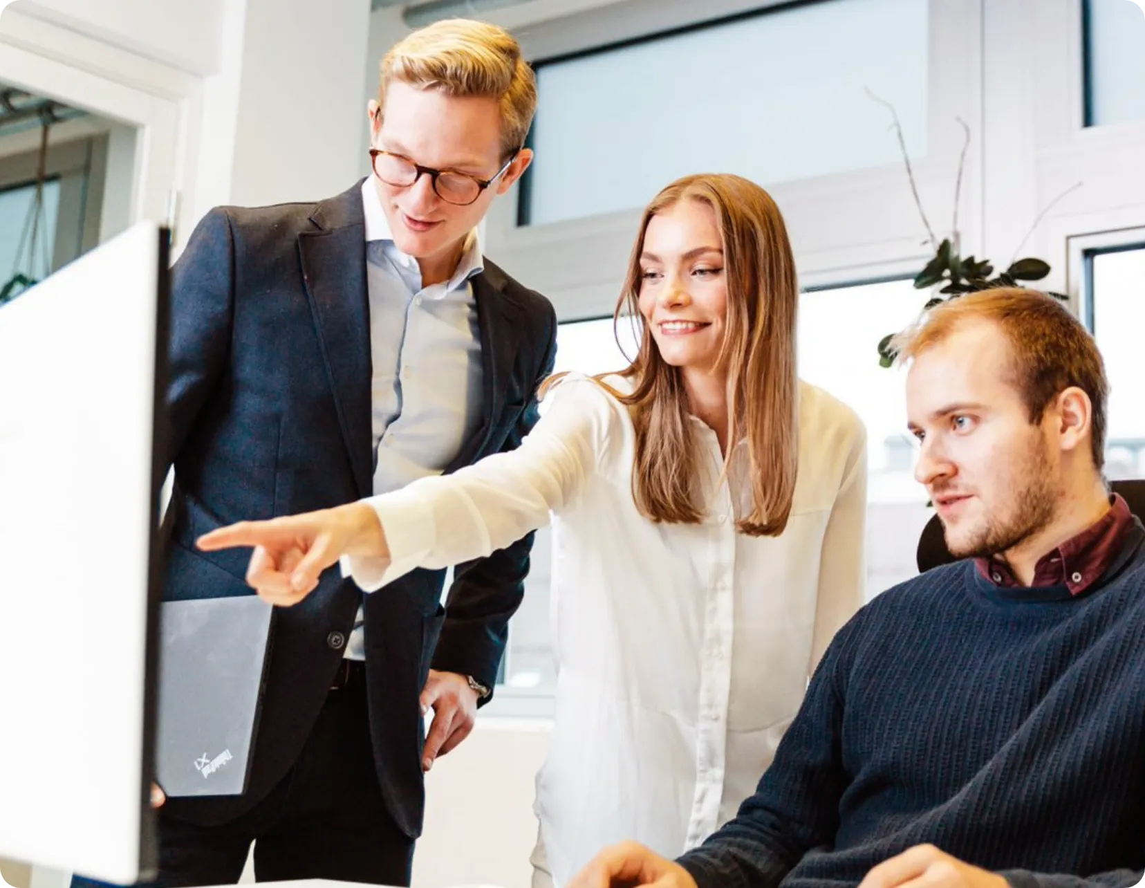 Three colleagues are collaborating while looking at a computer screen.